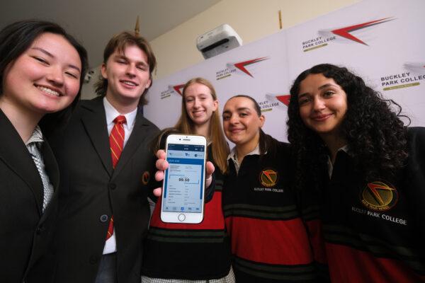 Buckley Park College students pose for a photograph as Emma Henrikson (centre) holds a phone showing her Australian Tertiary Admission Rank (ATAR) results on Victorian Certificate of Education (VCE) results day at Buckley Park College in Melbourne, Monday, Dec. 12, 2022. (AAP Image/Luis Ascui)