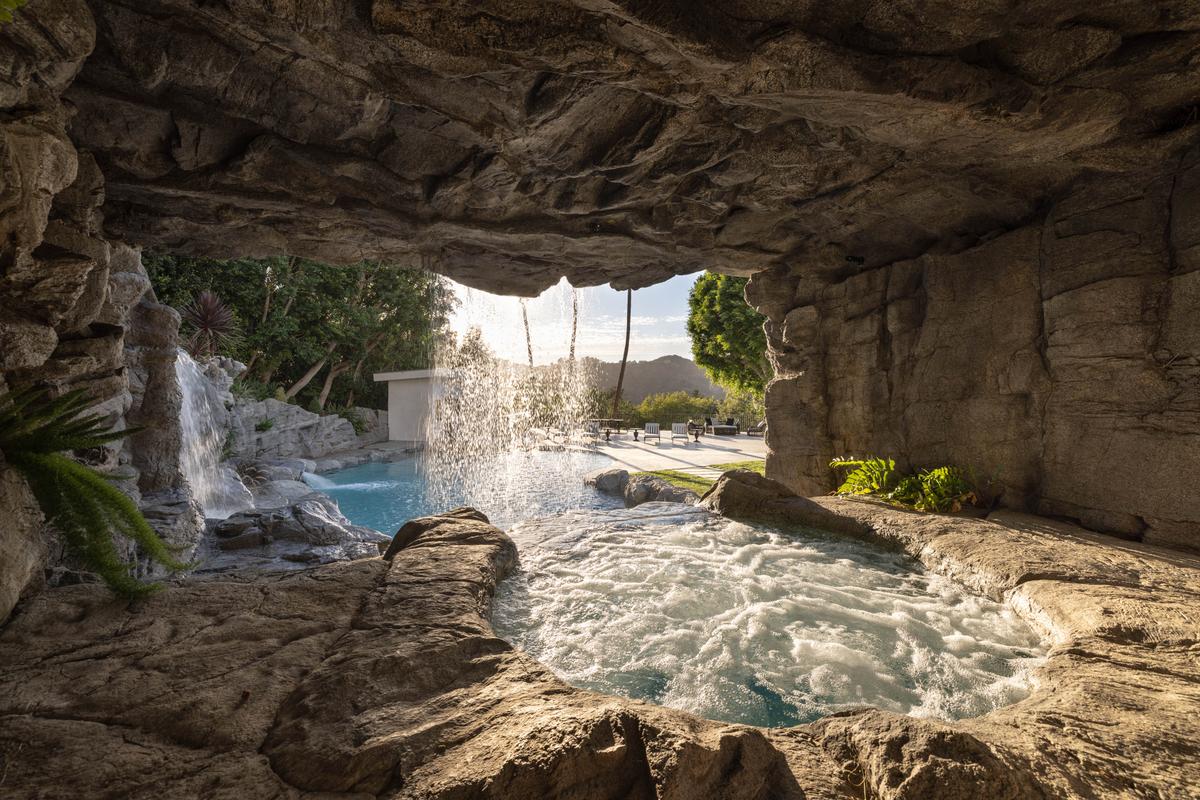 The pool’s grotto is the perfect place to escape the sun’s rays while relaxing in the hot tub, veiled by the waterfall. (Courtesy of Tyler Hogan and TopTenRealEstateDeals.com)