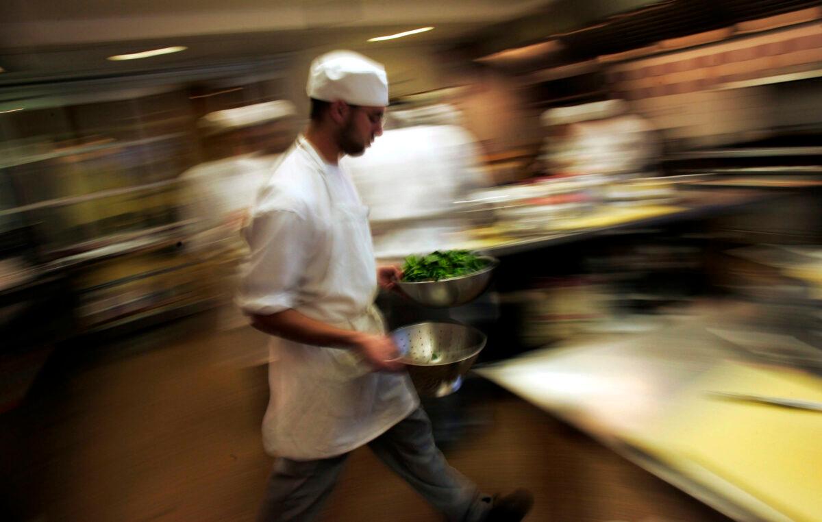 A culinary student rushes through the kitchen with greens during a class for aspiring professional chefs at The Institute of Culinary Education in New York City on Feb. 1, 2007. (Chris Hondros/Getty Images)