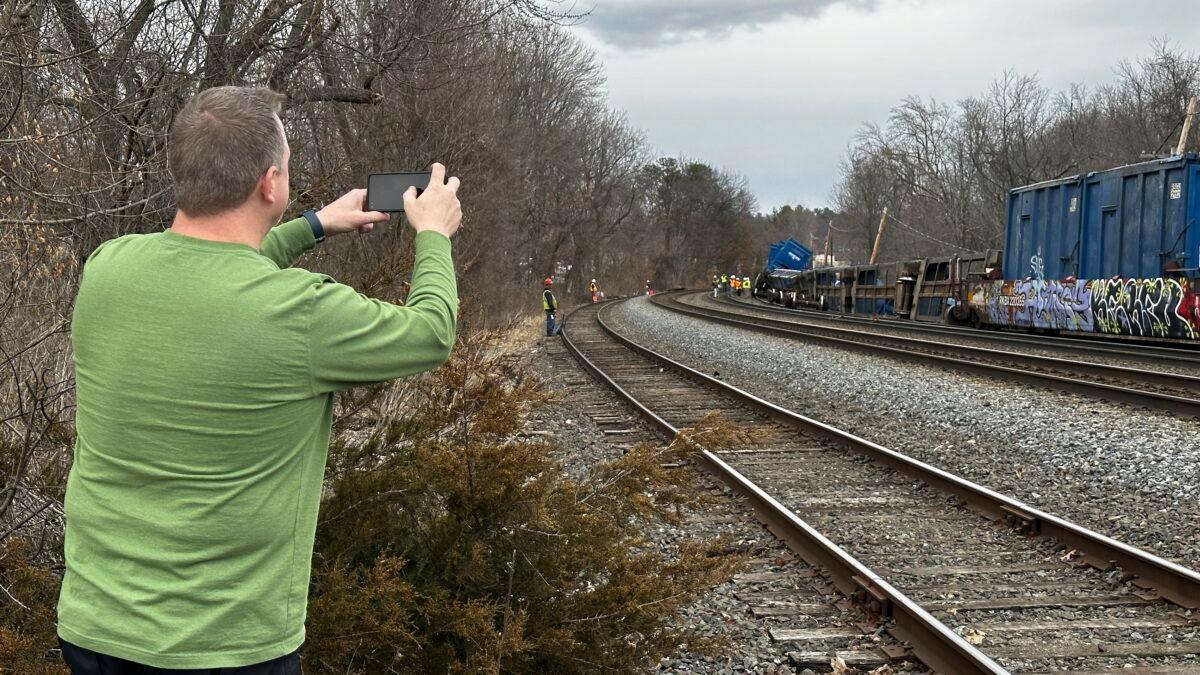 Scott Vacheresse photographs the scene of a freight train derailment in Ayer, Mass., on March 23, 2023. (Rodrique Ngowi/AP Photo)