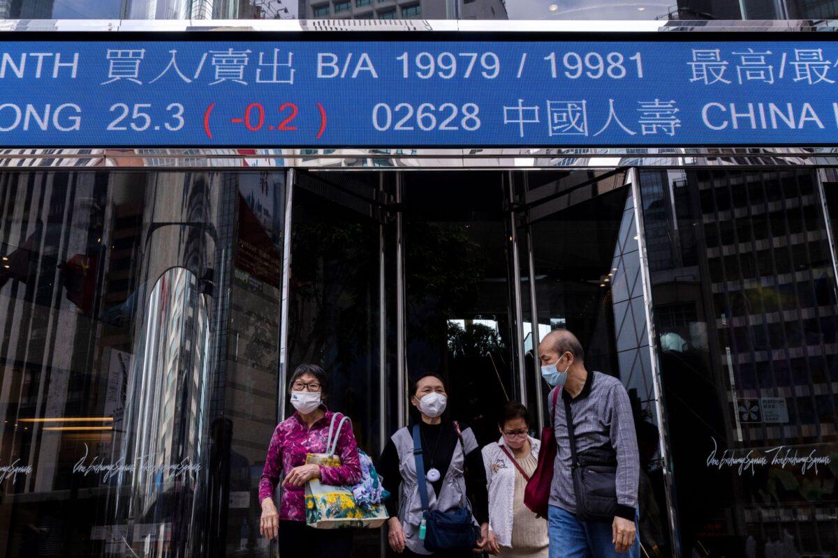Pedestrians pass by the Hong Kong Stock Exchange electronic screen in Hong Kong, on March 24, 2023. (Louise Delmotte/AP Photo)