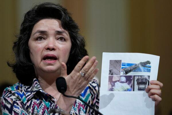 Qelbinur Sidik, a member of China's ethnic Uzbek minority who was forced to teach Chinese in separate detention facilities for Uyghur men and women, holds up images as she testifies during a special House committee hearing on the CCP in Washington on March 23, 2023. (Carolyn Kaster/AP Photo)