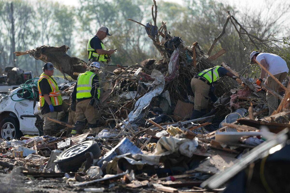 Emergency rescuers and first responders climb through a tornado-demolished mobile home park looking for bodies that might be buried in the piles of debris, insulation, and home furnishings in Rolling Fork, Miss., on March 25, 2023. (Rogelio V. Solis/AP Photo)