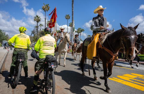 Saftey volunteers watch horseback riders trotting by during the Swallows Day Parade in San Juan Capistrano, Calif., on March 25, 2023. (John Fredricks/The Epoch Times)