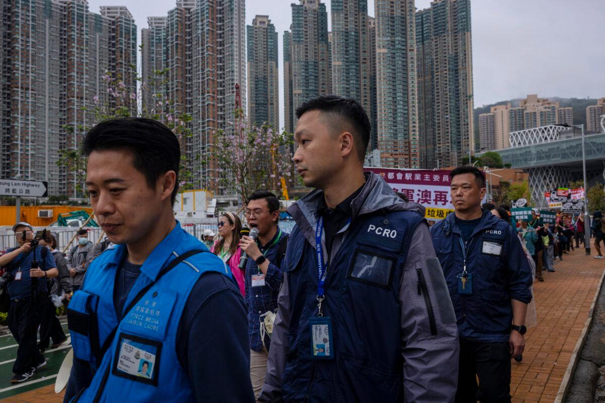 Police accompany protesters walking within a cordon line wearing number tags during a rally in Hong Kong on March 26, 2023. (Louise Delmotte/AP Photo)