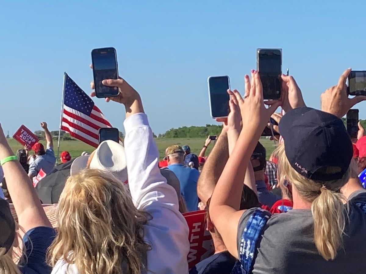 Attendees aim their cellphones skyward, hoping to get a shot of former President Donald Trump's private plane as it arrives at Waco Regional Airport in Texas on March 25, 2023. (Janice Hisle/The Epoch Times)