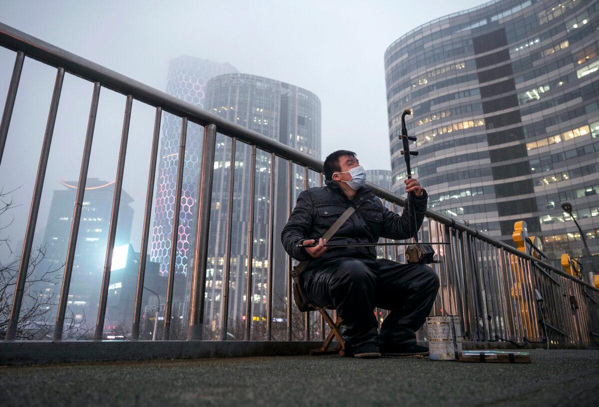 A visually impaired musician plays an erhu, a traditional Chinese stringed instrument, in a high-end shopping district in Beijing, on March 24, 2022. (Kevin Frayer/Getty Images)