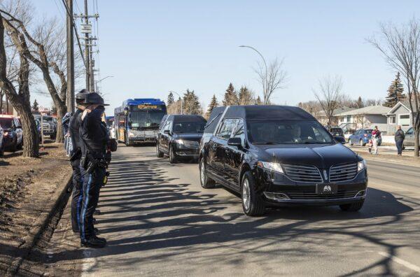 Police salute during a procession to a funeral home for Const. Travis Jordan and Const. Brett Ryan in Edmonton on March 21, 2023. (Jason Franson/The Canadian Press)