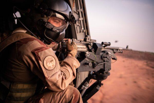 A soldier of the Barkhane force holds a weapon in a helicopter as he flies near Ouallam's military base, on July 15, 2022, during an official visit of French Ministers of Foreign Affairs and Armed Forces to Niger. (Bertrand Guay/AFP via Getty Images)