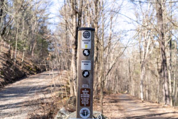 A post with directions and police contact info on a watershed trail in Port Jervis, N.Y., on March 16, 2023. (Cara Ding/The Epoch Times)
