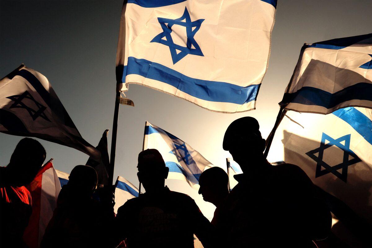 Israeli military veterans wave national flags during a rally against the government's judicial reform bill, along a highway near Netanya, Israel, on March 28, 2023. (Jack Guez/AFP via Getty Images)