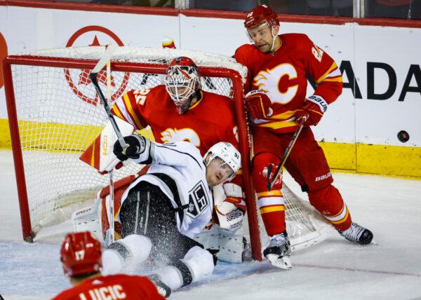 Los Angeles Kings forward Carl Grundstrom, center, crashes into Calgary Flames goalie Jacob Markstrom, as Flames forward Trevor Lewis hits the net during the third period of an NHL hockey game in Calgary, Alberta on March 28, 2023. (Jeff McIntosh/The Canadian Press via AP)