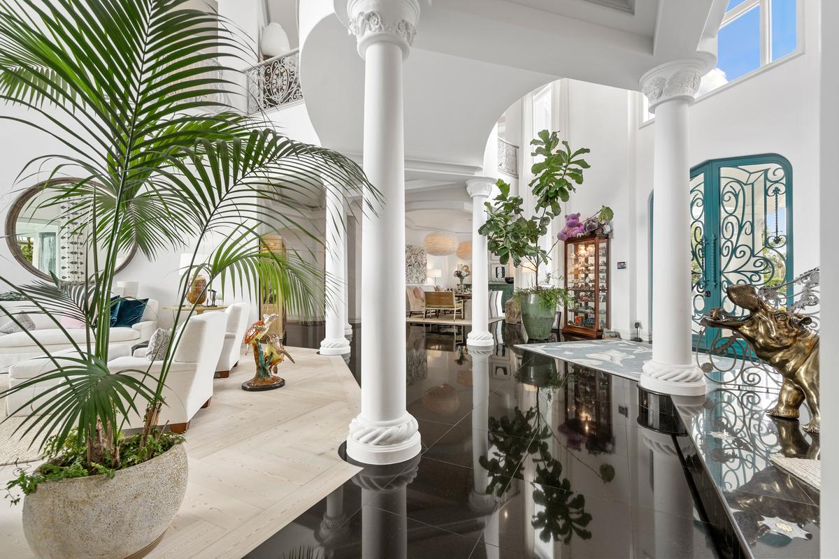 The interior of the home is as striking as the exterior, with double iron and glass doors opening onto the two-story-tall living room, with a mezzanine-level walkway above leading to bedrooms and common areas. (Courtesy of James Northen / ONE Sotheby's International Realty)