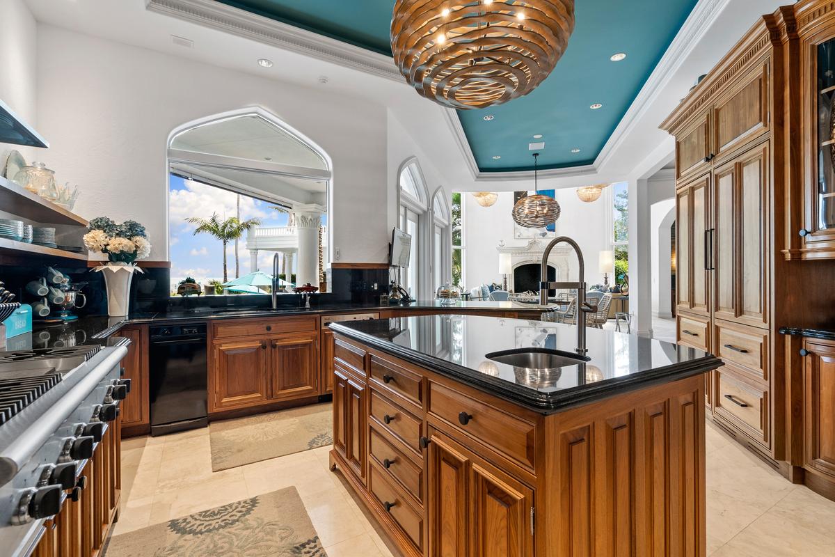 Located adjacent to the living room and formal dining room, the well-equipped kitchen features restaurant-grade appliances, custom cabinetry, and a perfect view of the pool area. (Courtesy of James Northen / ONE Sotheby's International Realty)