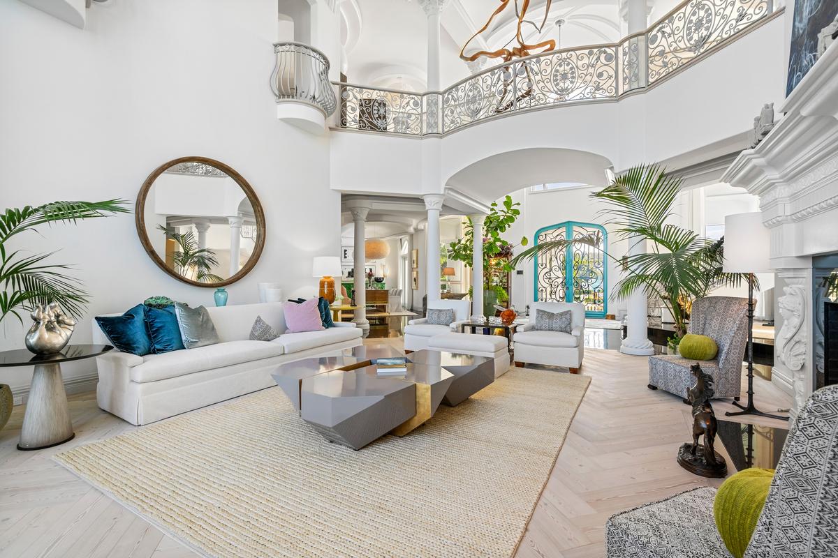The exceptionally airy living room is just inside the main doors and accented by an oversized fireplace, with the second level’s walkway and Juliette balcony above. (Courtesy of James Northen / ONE Sotheby's International Realty)