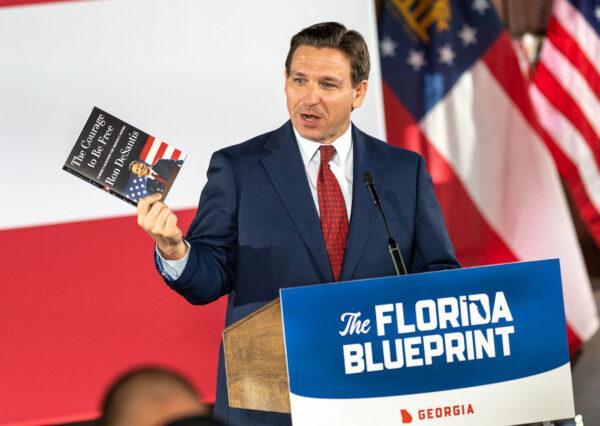 Florida Gov. Ron DeSantis hawks his book at a book tour speech in Smyrna, Ga. on March 30, 2023. (Phil Mistry/The Epoch Times)