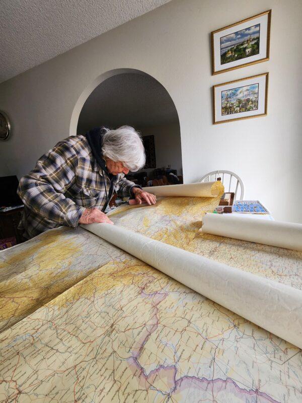 George Ilinsky pores over German war maps used during World War II on March 21, 2023. (Allan Stein/The Epoch Times)