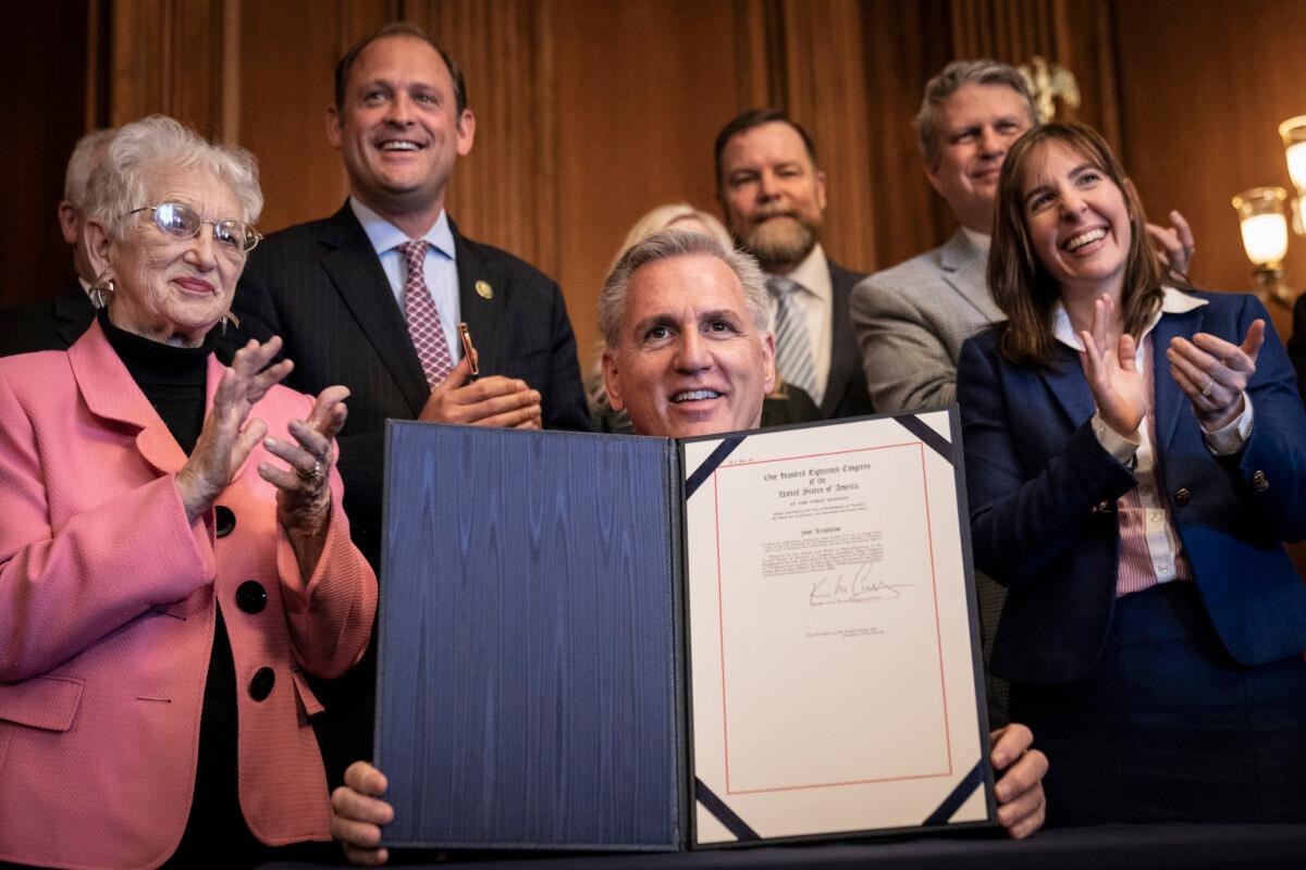 House Speaker Kevin McCarthy (R-Calif.), with Kentucky State Treasurer Allison Ball standing behind him (R), signs a resolution to block a Biden administration rule encouraging retirement managers to consider environmental, social, and corporate governance (ESG) factors when making investment decisions, during a bill signing ceremony at the U.S. Capitol on March 9, 2023. (Drew Angerer/Getty Images)