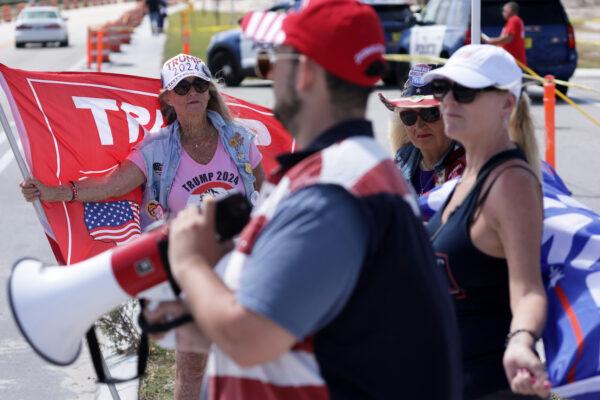 Supporters of former U.S. President Donald Trump hold flags as they gather to show support near his Mar-a-Lago home in Palm Beach, Fla., on March 31, 2023. (Alex Wong/Getty Images)