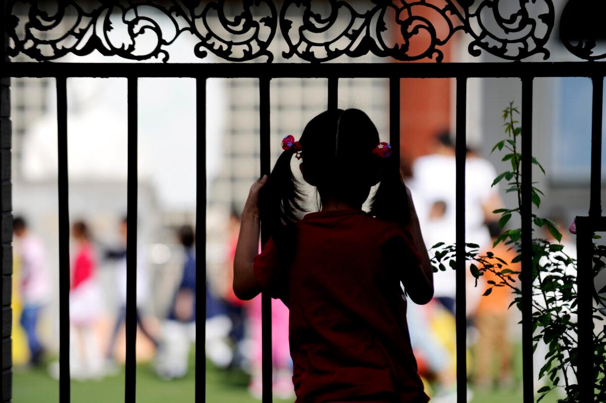 A girl is looking through a fence in Beijing on Sept. 19, 2012. (Wang Zhao/AFP/GettyImages)
