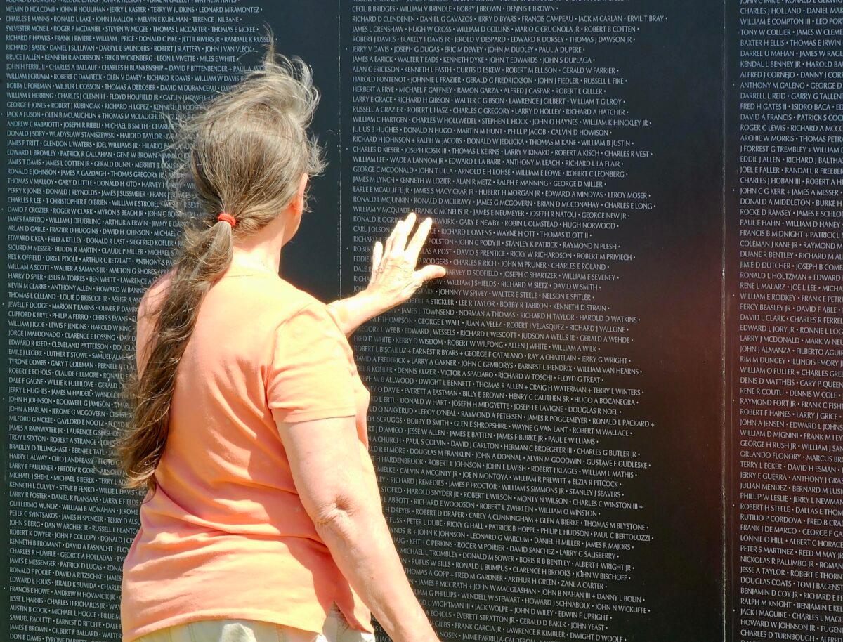 A visitor touches the Vietnam veterans traveling memorial wall in Camp Verde, Ariz., on March 29, 2023. (Allan Stein/The Epoch Times)