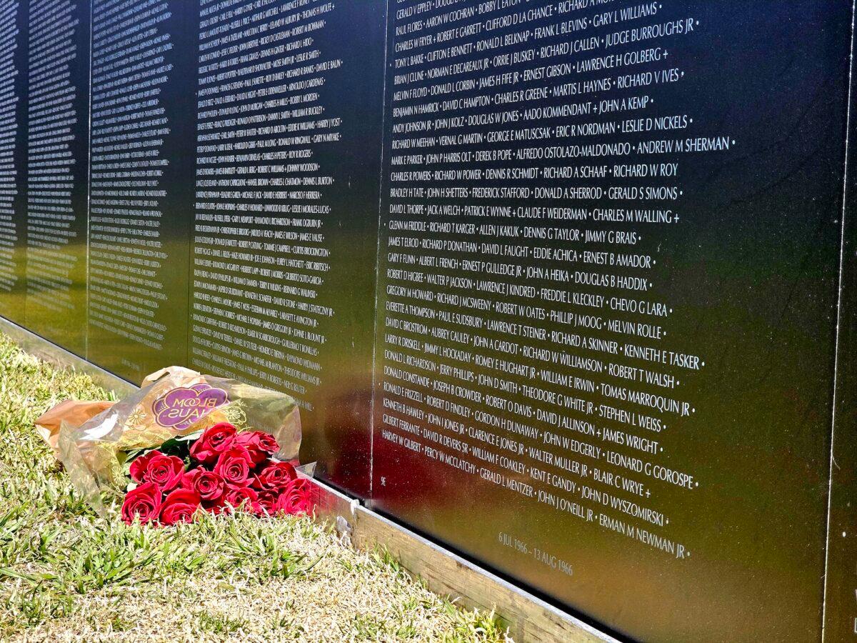 A bouquet of red roses lies at the foot of the Vietnam veterans traveling memorial wall in Camp Verde, Ariz., on March 29, 2023. (Allan Stein/The Epoch Times)