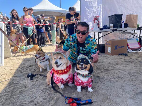 Dan McLemore, host of the 11th annual Corgi Beach Day, poses with corgi attendees in Huntington Beach, Calif., on April 1, 2023. (Carol Cassis/The Epoch Times)