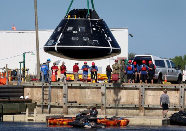 Members of the US Navy and NASA Landing and Recovery Team use a crane to remove a test version of the Orion capsule from the water after practicing retrieving astronauts from it in in Cape Canaveral, Fla., on Feb. 6, 2023. (Joe Raedle/Getty Images)