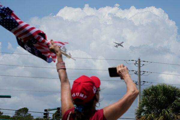 A supporter of former President Donald Trump waves as his plane takes off from Palm Beach International Airport in West Palm Beach, Fla., on April 3, 2023. (Wilfredo Lee/AP Photo)