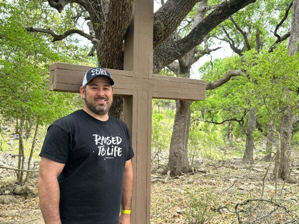 Tristen Cleve, executive director of Hays County CCDF in Texas, places a cross among the live oak trees near an outdoor festival that hosted music with occult themes on April 1, 2023. (Darlene McCormick Sanchez/ The Epoch Times)