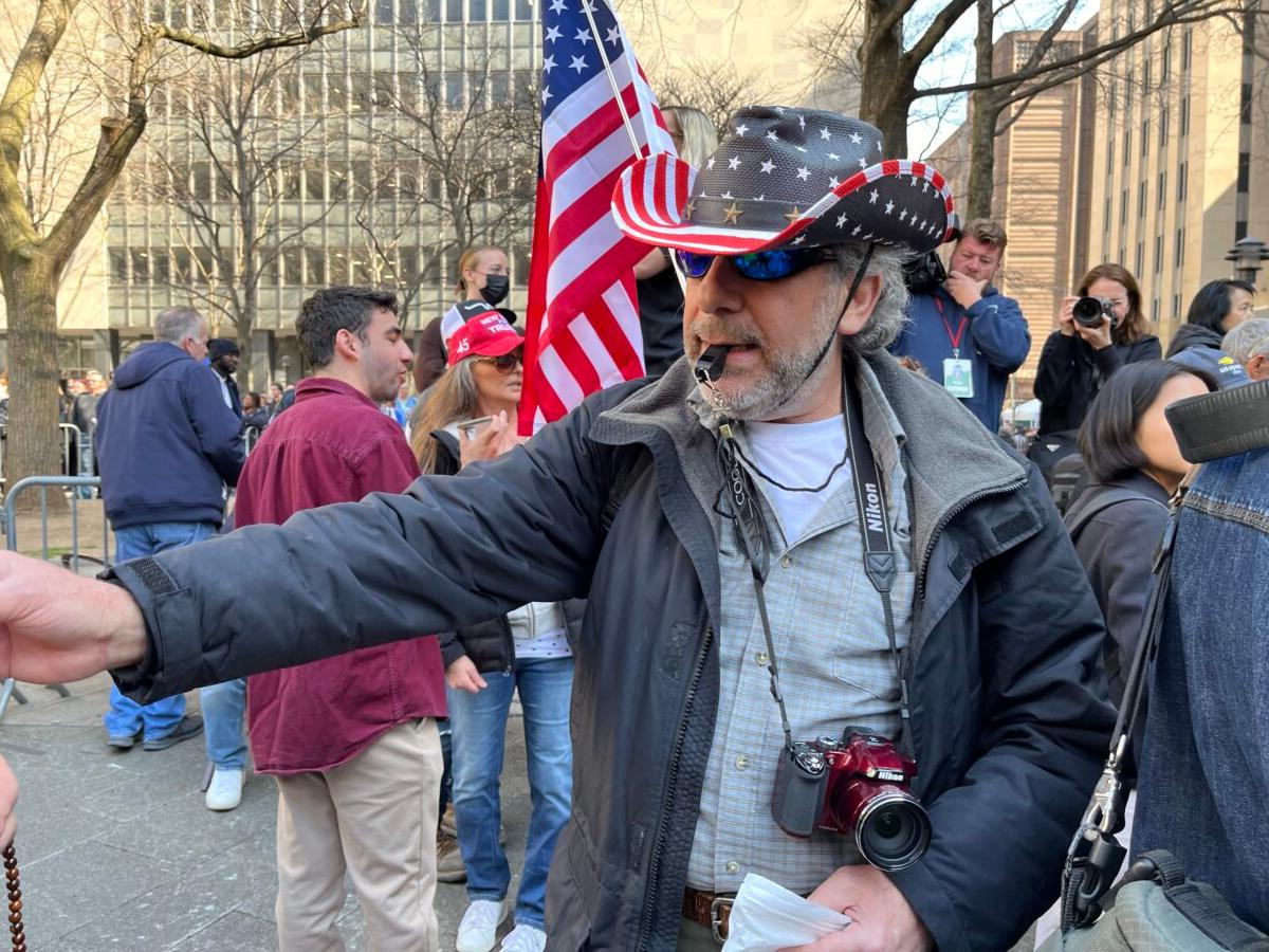 A Trump supporter hands out whistles to Trump supporters in New York on April 4, 2023. (Eva Fu/The Epoch Times)