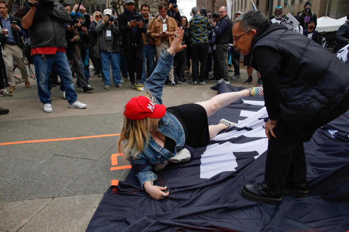 A Trump supporter removes a banner from anti-Trump protesters outside the Manhattan Criminal Courthouse on April 04, 2023 in New York City. (Kena Betancur/Getty Images)