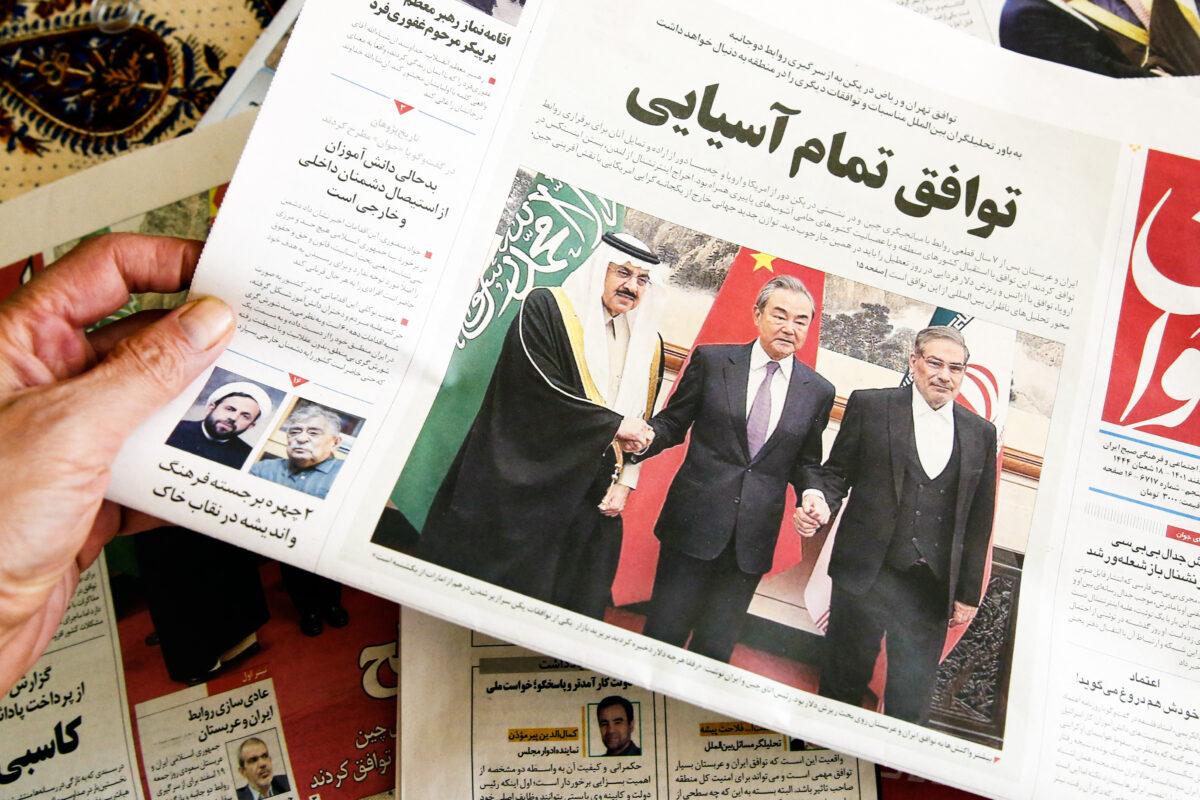 A man holds a local newspaper reporting on the China-brokered deal between Iran and Saudi Arabia to restore ties, in the Iranian capital Tehran on March 11, 2023. (Atta Kenare/AFP via Getty Images)