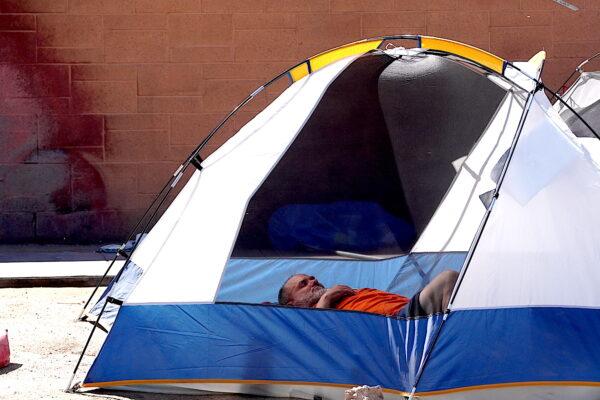 A homeless man lies sleeping in his dome tent in the Zone in Phoenix on April 3, 2023. (Allan Stein/The Epoch Times)