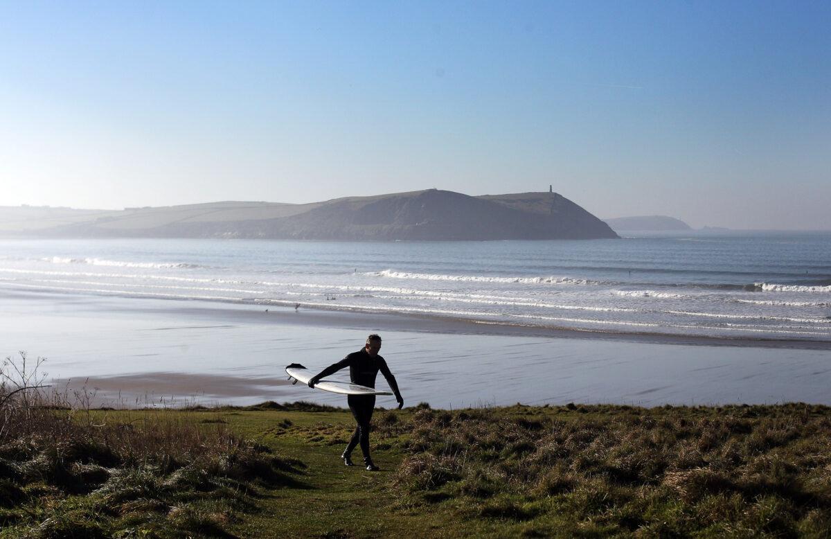 A surfer makes his way from the beach after braving the winter waves in Polzeath, England, on Jan. 20, 2011. (Matt Cardy/Getty Images)