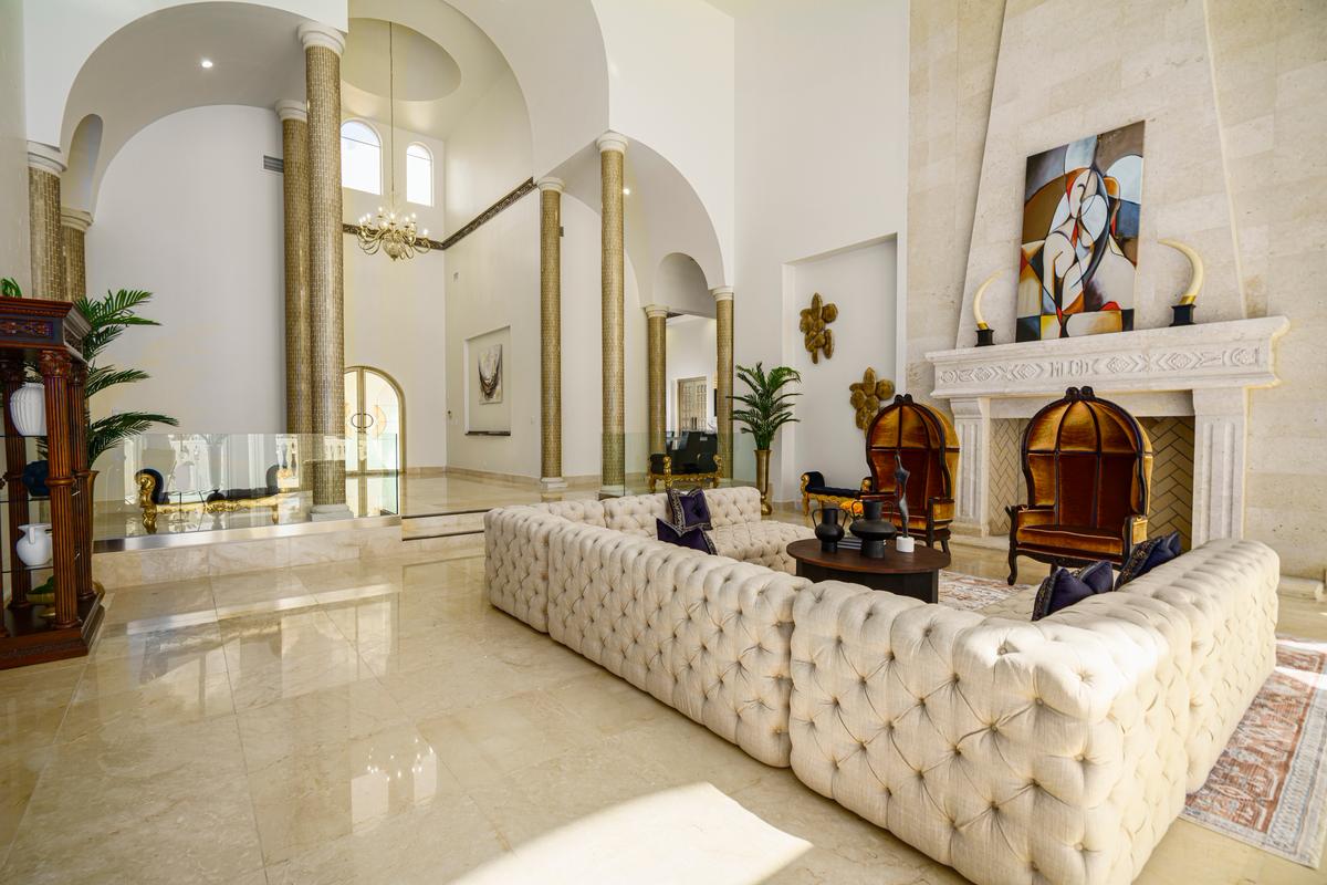 The home's doors open onto a two-story-tall foyer accented by gleaming marble floors and towering columns, with the living room and a magnificent fireplace just beyond. (Courtesy of The Carroll Group)