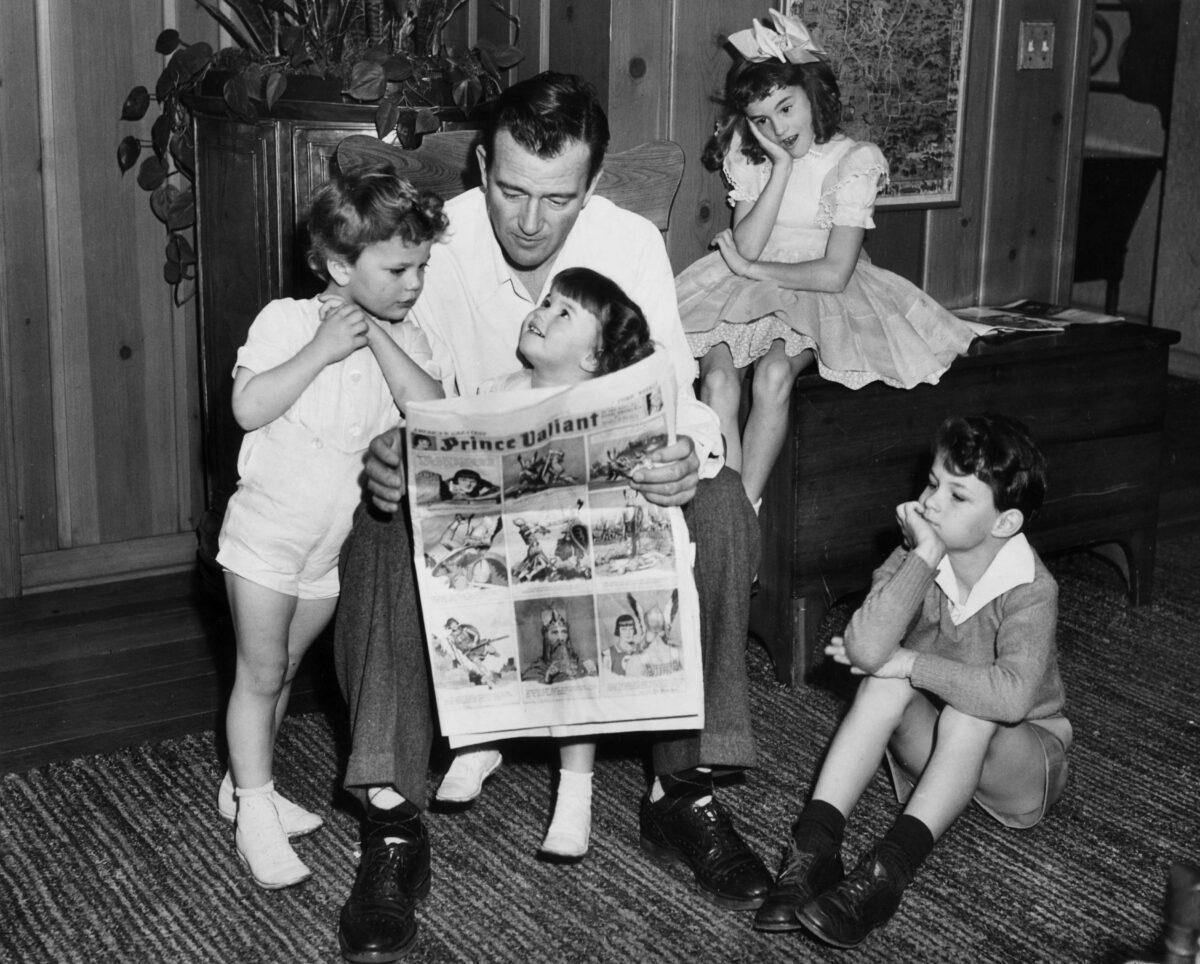Wayne reads a “Prince Valiant” comic with his four children, 1942. (Hulton Archive/Stringer/ Archive Photos/Getty Images)
