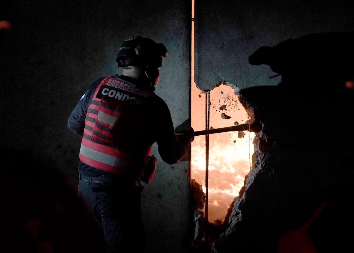 A firefighter breaches a wall to help extinguish a fire at the Central de Abasto wholesale market, the main food distribution center, in Mexico City on April 6, 2023. (Eduardo Verdugo/AP Photo)