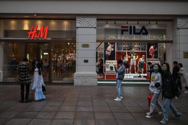 People walk past shopfronts for Swedish clothing giant H&M and Italian sportswear company Fila in Shanghai, China, on March 26, 2021. (Hector Retamal/AFP via Getty Images)