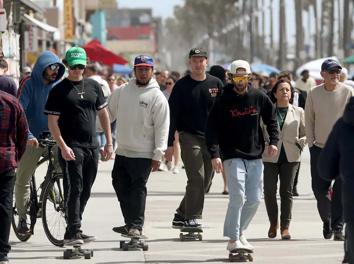From left, Lawrence Doherty, Daniel Galan, Ryan Fonseca and Braden Walker skateboard on the Venice Beach boardwalk for a bonus segment of the California Double, which includes surfing and snowboarding in the same day, in Los Angeles. (Luis Sinco/Los Angeles Times/TNS)