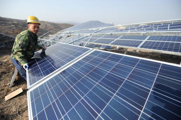 A worker installs polycrystalline silicon solar panels as a terrestrial photovoltaic power project starts in Guanshui Town of Muping District in Yantai, Shandong Province, China, on Nov. 17, 2015. (VCG/VCG via Getty Images)