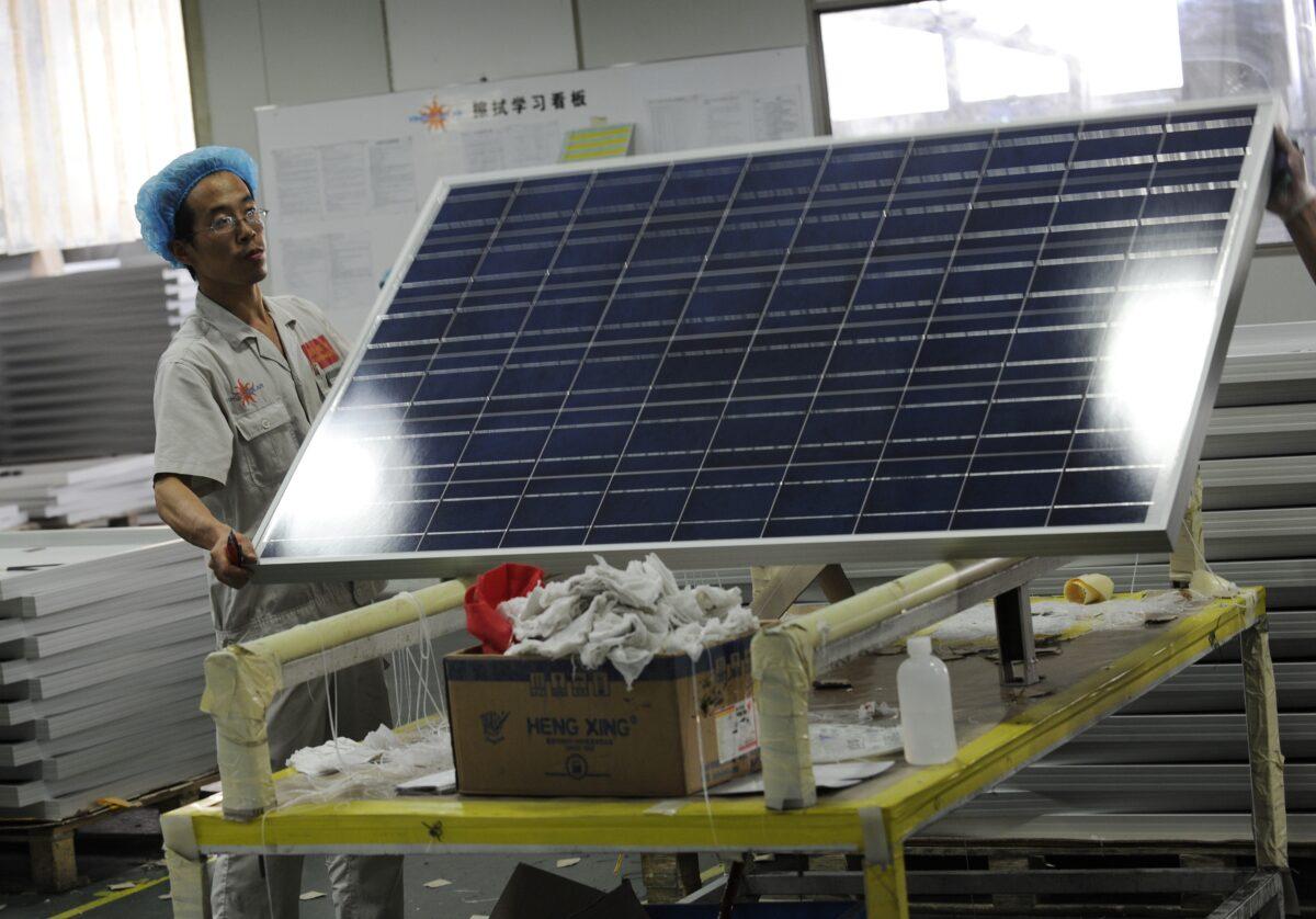 A worker lifts a solar panel in the Yingli Solar factory, a leading solar energy company and one of the world's largest manufacturers of solar panels in Baoding, Hebei province, on Sept. 30, 2010. (PeterR Parks/AFP via Getty Images)