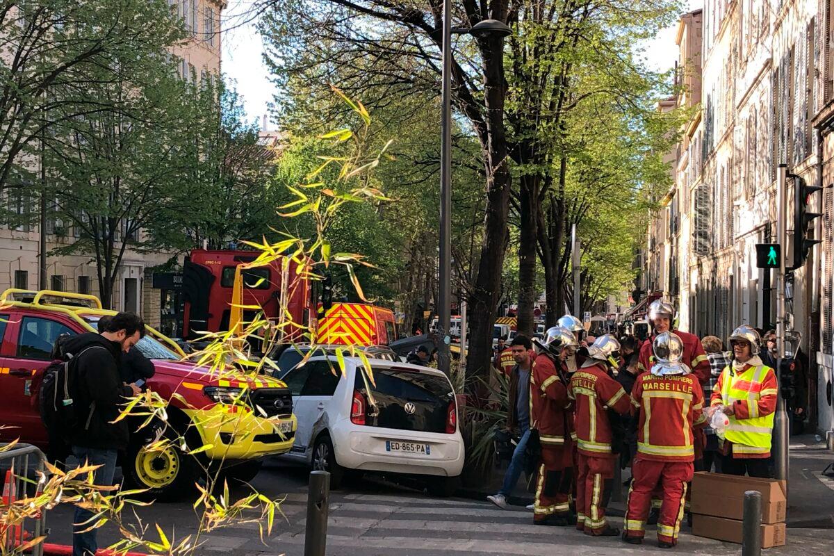 Firefighters gather near the street where a building collapsed in Marseille, southern France, early on April 9, 2023. (Bishr El Touni/AP Photo)