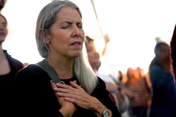 A woman holds her hands to her chest in prayer during a tent ministry in Bakersfield, Calif., on March 12, 2023. (Allan Stein/The Epoch Times)