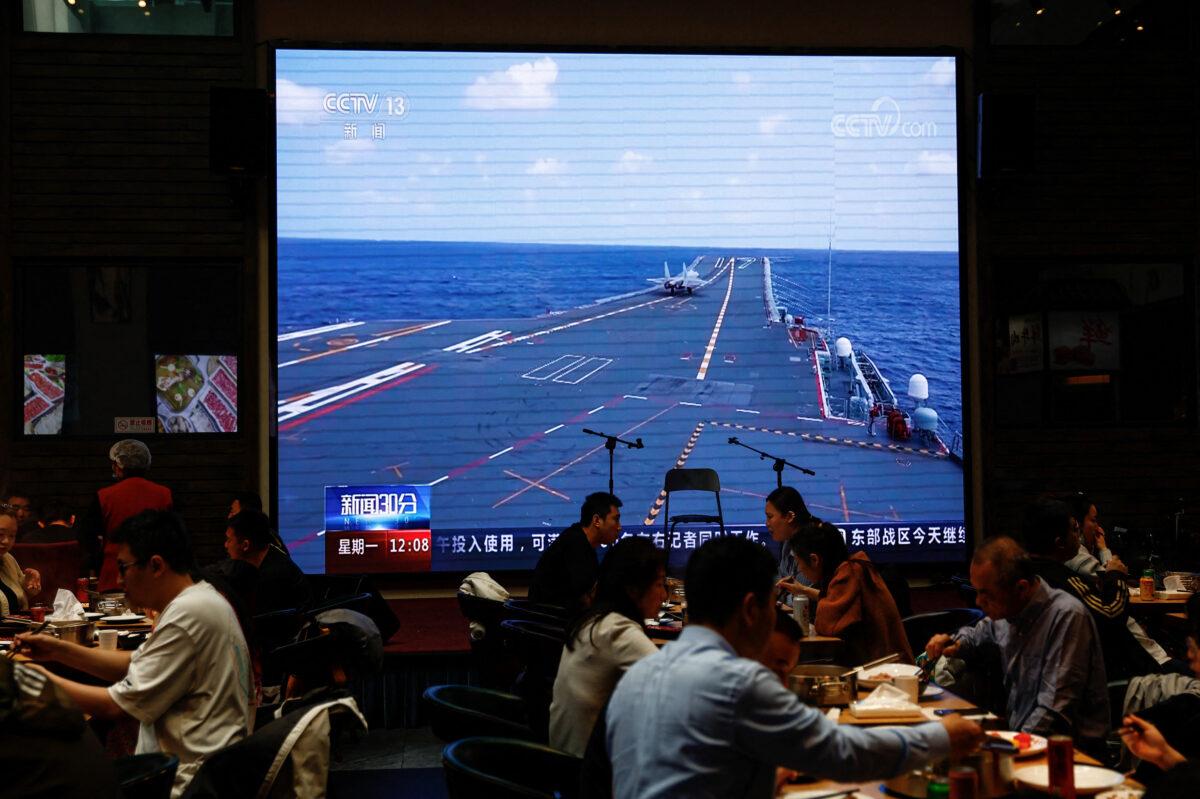 Customers dine near a giant screen broadcasting news footage of aircraft under the Eastern Theatre Command of China's People's Liberation Army (PLA) taking part in a combat readiness patrol and "Joint Sword" exercises around Taiwan, at a restaurant in Beijing on April 10, 2023. (Tingshu Wang/Reuters)