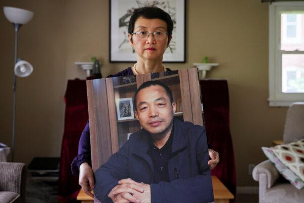 Sophie Luo Shengchun, the wife of jailed Chinese human rights lawyer Ding Jiaxi, poses with a photo of him at her home in Alfred, N.Y., on July 28, 2022. (Brendan McDermid/Reuters)