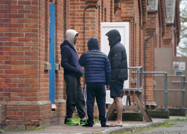 Illegal immigrants who crossed the English Channel in small boats stand talking to each other at their temporary home at Napier Barracks in Folkestone, Kent, on March 7, 2023. (PA)