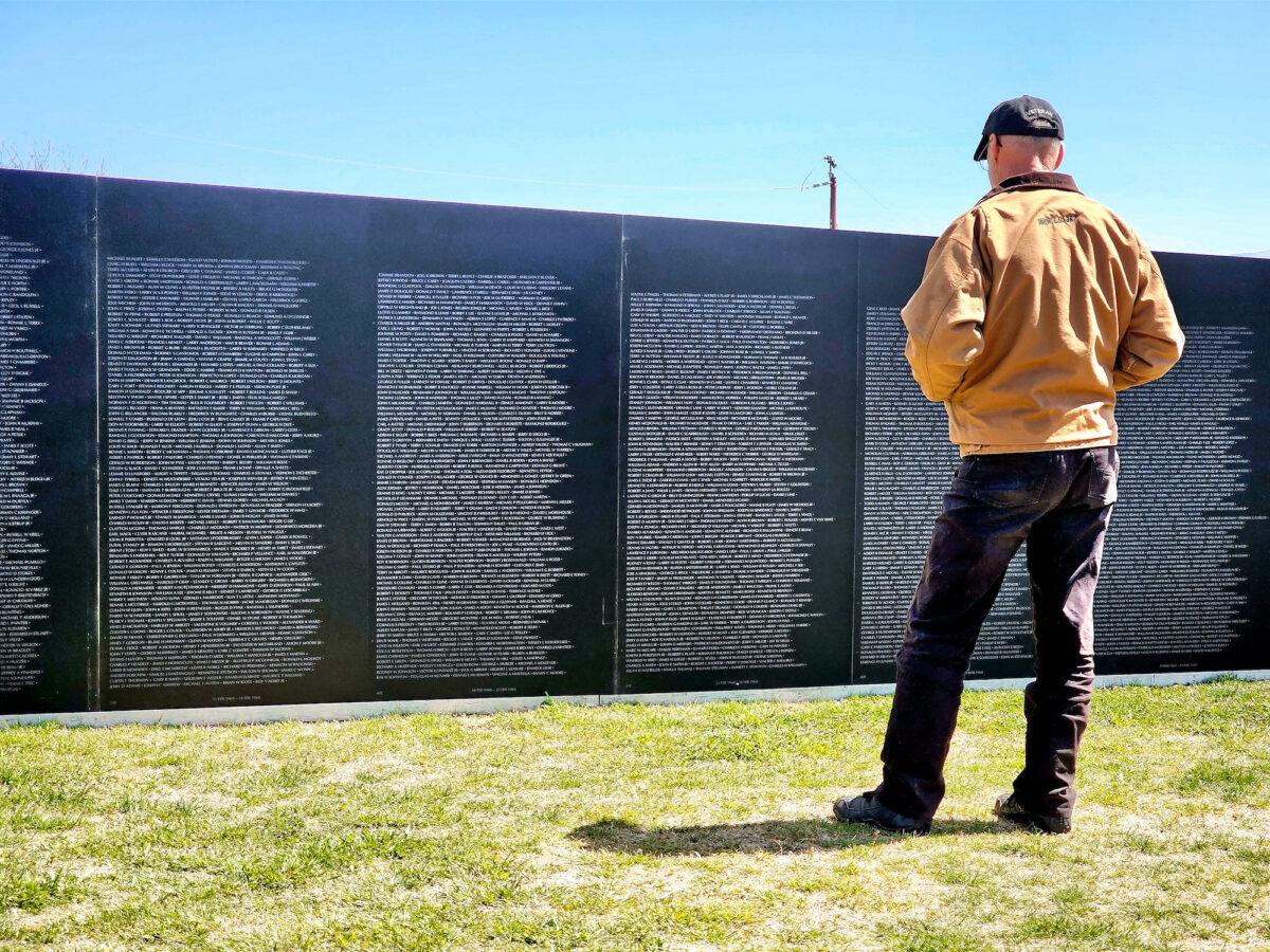 A visitor pays homage at the Vietnam veterans traveling wall in Camp Verde, Ariz., on March 29, 2023. (Allan Stein/The Epoch Times)
