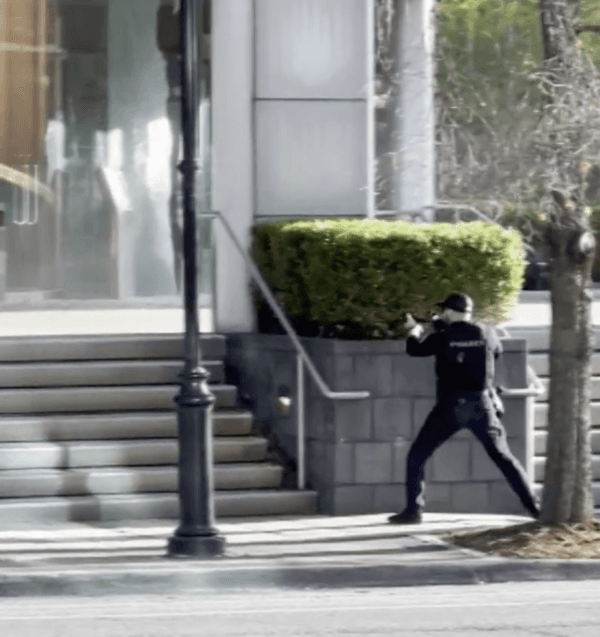 Officer Cory Galloway takes cover behind a concrete planter during an ongoing shooting incident captured by a bystander at Old National Bank in Louisville, Ky., on April 10, 2023, in this screengrab. (Louisville Metro Police Department/Screenshot via The Epoch Times)