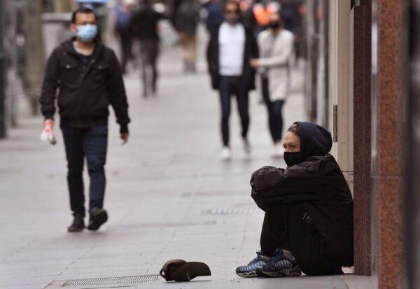 A man begs for money along a street in Melbourne's city center on Sept. 17, 2020. (William West / AFP via Getty Images)